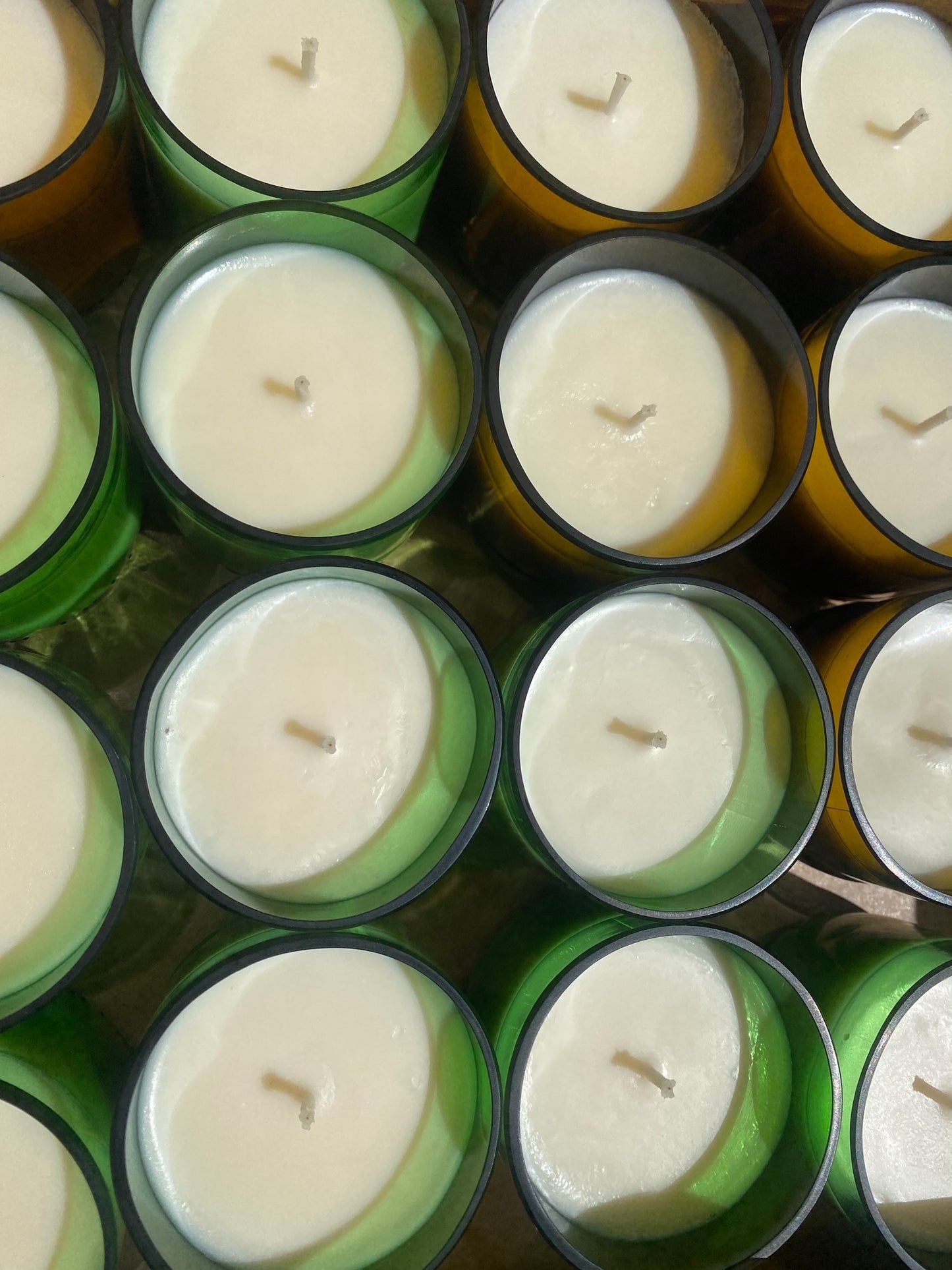 Soy candles in a an up-cycled green and brown glass beer bottles grouped together