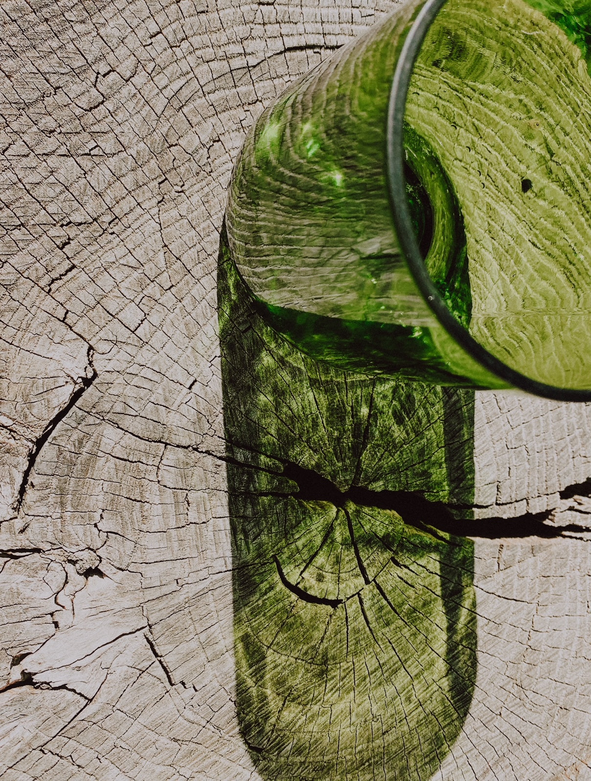 a cut in half beer bottle on a wood showing the reflection of the glass