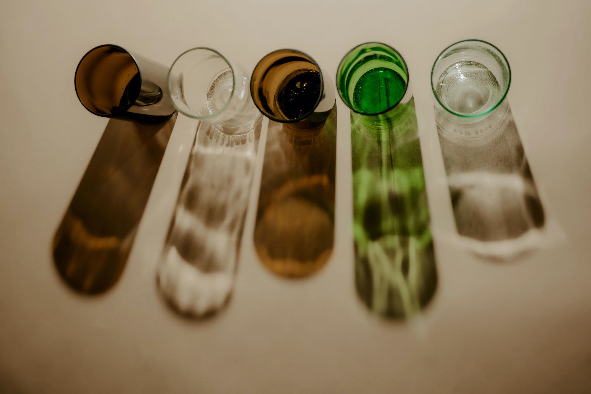 different colour beer glass bottles cut in half with reflection